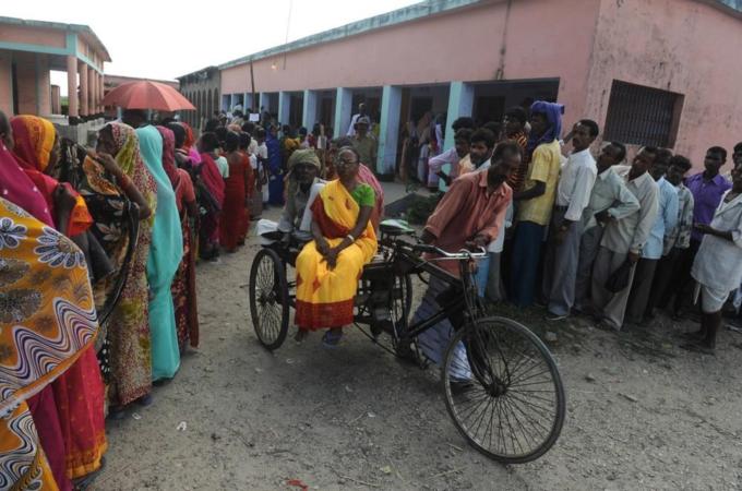 Elderly voters ride on a cycle rickshaw