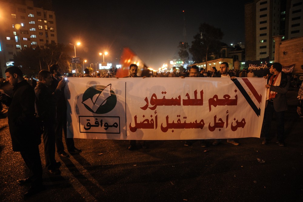 Members of the Muslim Brotherhood march with a banner that reads, "Yes to the constitution, for a better future" in Nasr City, Cairo. Rival sides in Egypt are staging rallies a
day before the first round of voting begins on a contentious draft
constitution.