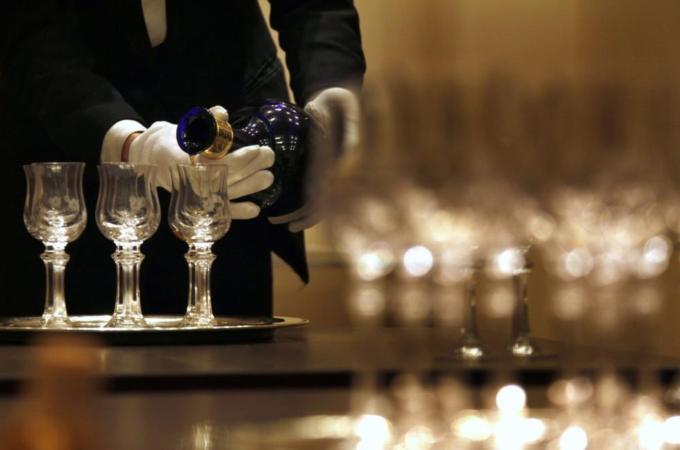 A waiter is reflected in a mirror as he pours luxury Scotch whisky Royal Salute into glasses in Beijing