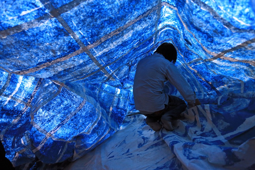 A man stacks mulberry paper inside a hot air balloon during its construction.