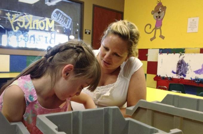 Godwin, an insurance claims supervisor, helps her daughter Grace draw pictures in Parker