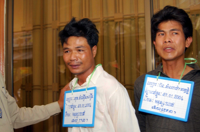 Sok Samoeun (C) and Bond Samnang (R) are escorted by police