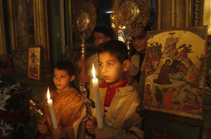 Palestinian Christian boys hold candles during a service in the Saint Porfirios church in Gaza City on Christmas day [Reuters]