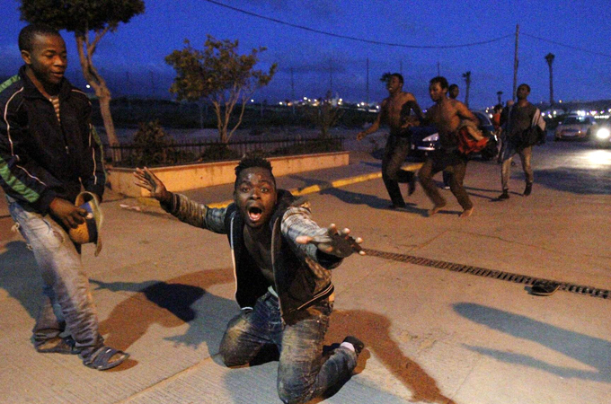 African migrants celebrate after hundreds managed to jump fences into Melilla, Spain in late May [EPA]