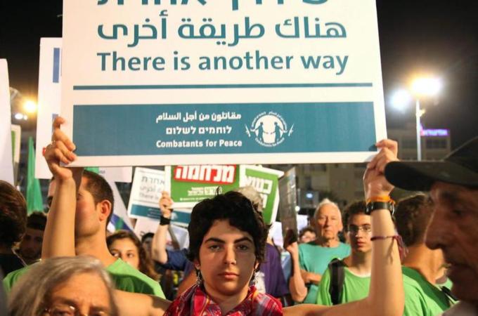 An Israeli holds a placard written in Arabic, Hebrew, and English during a peace protest in Rabin Square in Tel Aviv  [EPA]