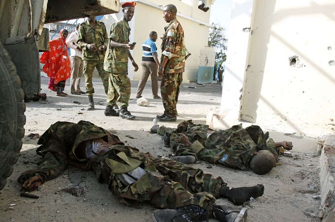 Somali soldiers look at the bodies of al-Shabab fighters near the presidential palace in Mogadishu in July [AP]
