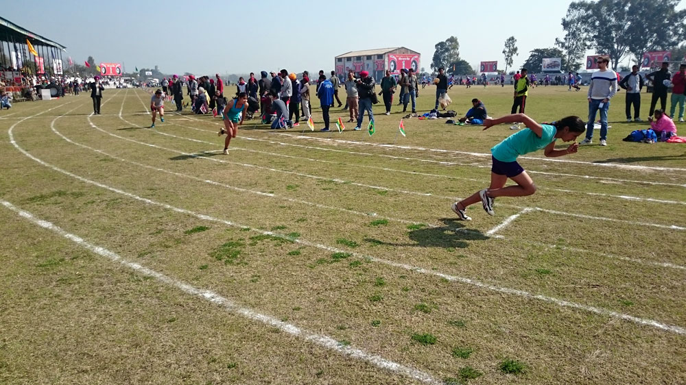 Women mid-stride in the 400 meter sprint. Women have always participated in track and field events at Kila Raipur [T. Thomas Koshy/Al Jazeera]