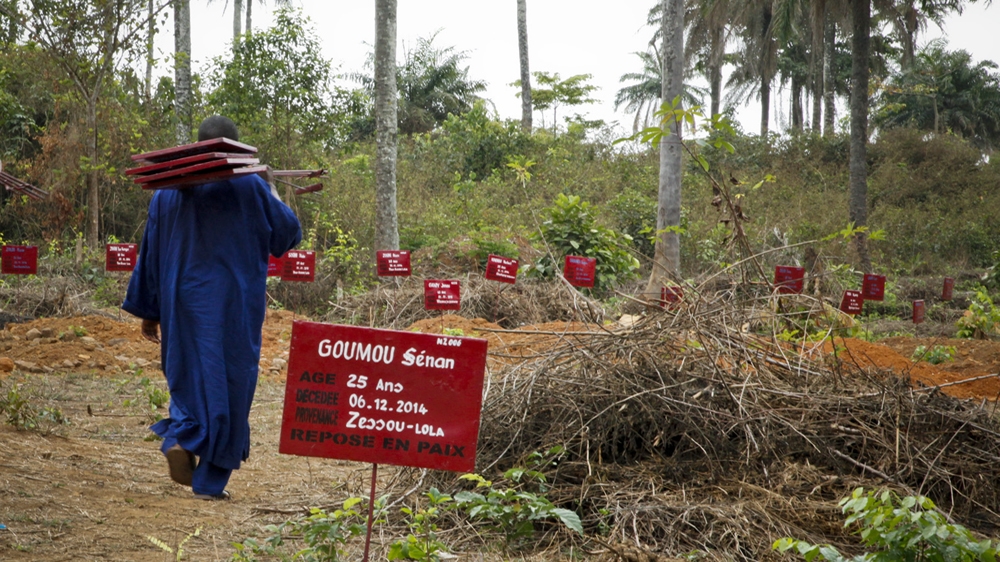 A Red Cross worker in Nzerekore in southeast Guinea removes metal grave markers [Misha Hussain/Thomson Reuters Foundation]