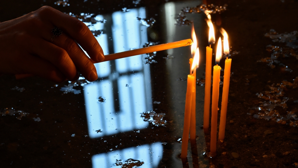 A woman lights a candle at the cathedral in Yerevan, ahead of the canonization ceremony for the Martyrs of the Armenian Genocide. [AFP]