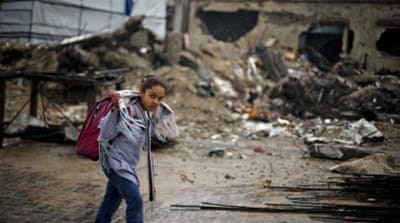 Palestinian schoolgirl walks past the rubble of a house in Gaza [REUTERS]