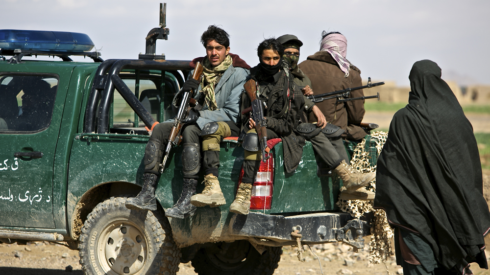 Afghan police look on as an angry farmer approaches them during an operation to destroy poppy fields [Steve Chao/Al Jazeera]