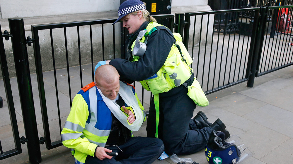 An injured police officer is helped by a colleague during clashes with demonstrators [Reuters]