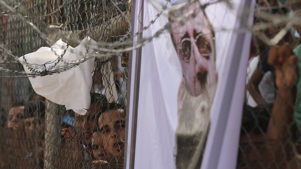 Fans in Gaza City stand behind a poster of Khader Adnan as they watch the Gaza Strip Cup final match [Mohammed Salem/Reuters]
