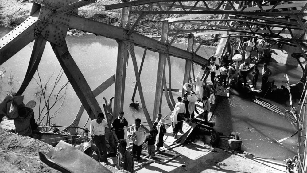 Palestinian refugees cross the remains of the Allenby Bridge over the River Jordan, after it was blown up to prevent Israeli pursuit during the Six Day War [Getty Images]