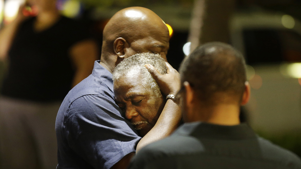 Worshippers embrace after a group prayer across the street from the scene of a shooting in Charleston [AP]