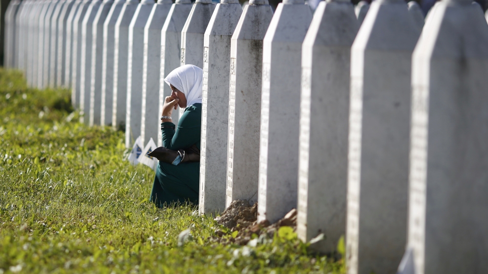 A woman mourns among graves in Memorial Center Potocari, near Srebenica
