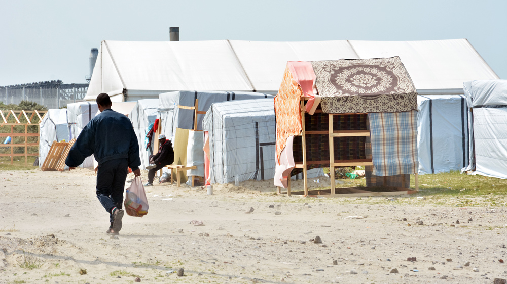 Fences separating Jules Ferry refugee camp and the N216 motorway, leading to the ferry terminal, surround the camp [Ben Gerdziunas/Al Jazeera]
