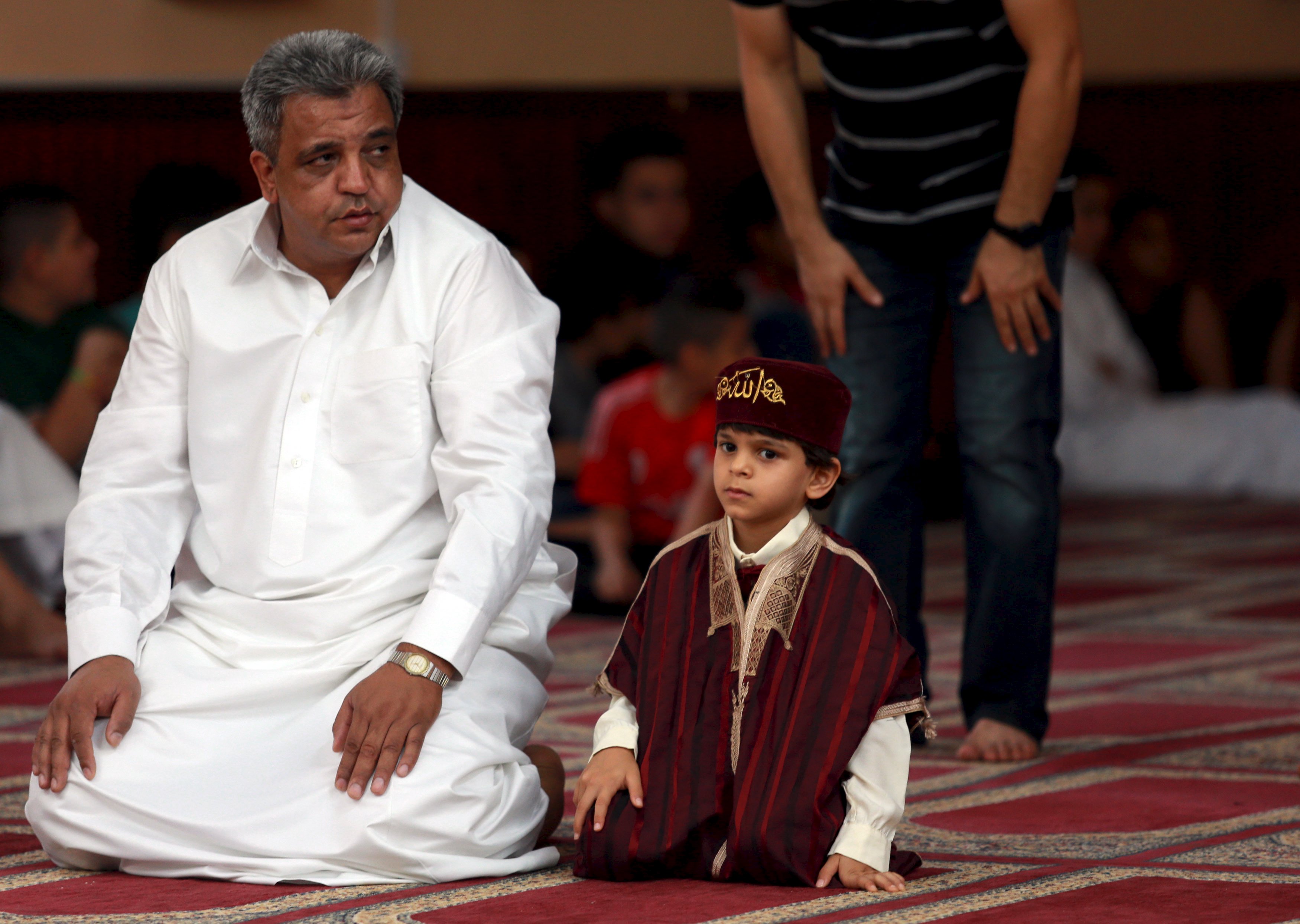 A boy waits for prayers with his father at a mosque during Eid al-Fitr to mark the end of Ramadan in Benghazi, Libya July 17, 2015. REUTERS/Esam Omran Al-Fetori