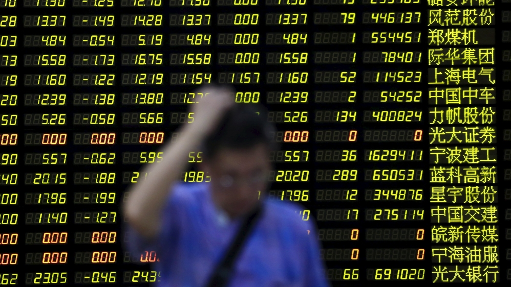 An investor stands in front of electronic board showing stock information at brokerage house in Shanghai