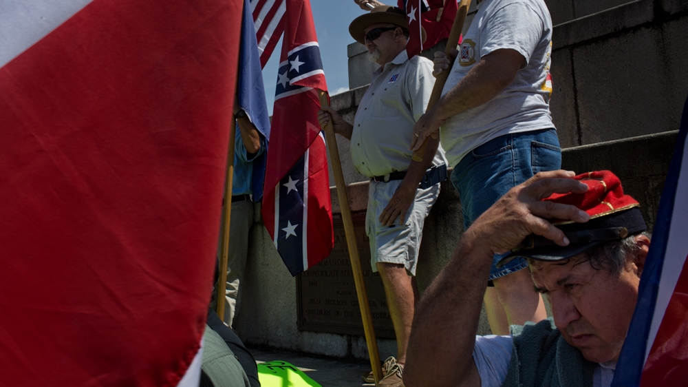 Protesters gather around a statue of Robert E Lee. 'I'm offended by a lot of stuff in life, but I simply deal with it and move on,' said one member of the United Daughters of the Confederacy. 'This statue should not come down and it will be over my dead body' [Roopa Gogineni]