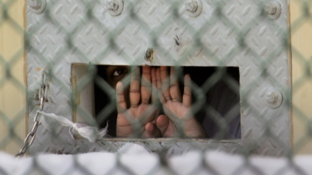 A detainee peers out through the so-called ‘bean hole’, used to pass food and other items into detainee cells, at Camp Delta detention centre at Guantanamo Bay US Naval Base, Cuba