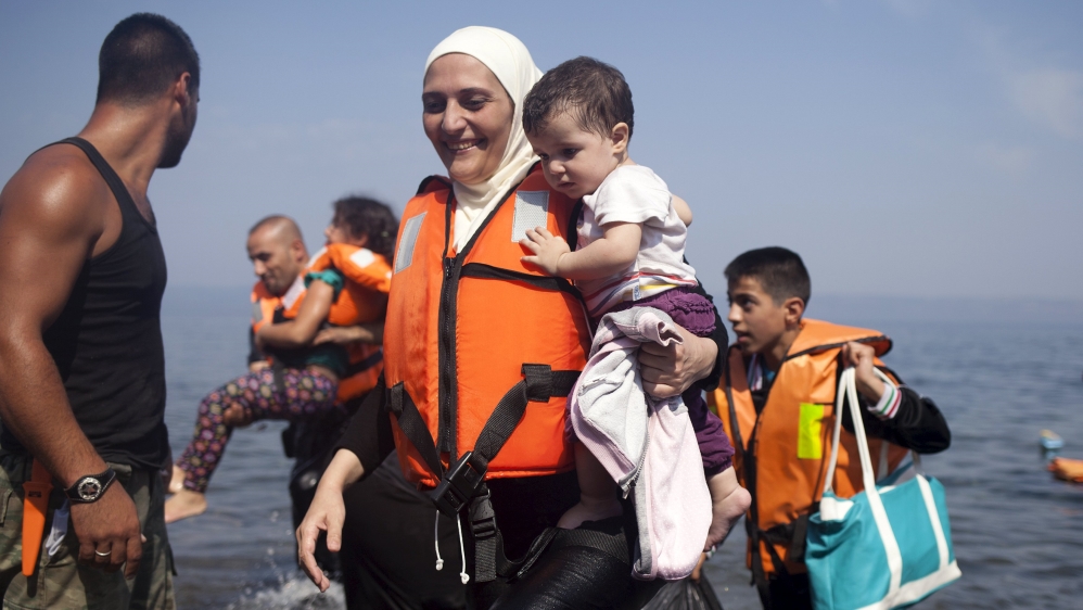 A Syrian refugee holds a child moments after arriving on a dinghy on the Greek island of Lesbos [REUTERS]
