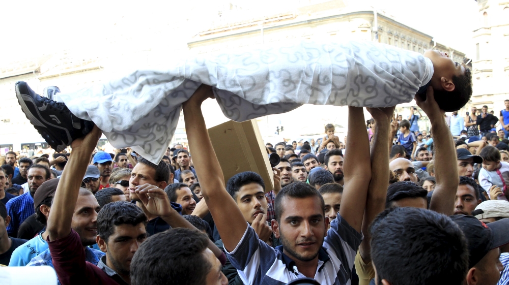 Protesting refugees from Afghanistan and Syria hold up a child wrapped in blankets as a reminder of the horrors they have fled while demonstrating in Budapest [Reuters]