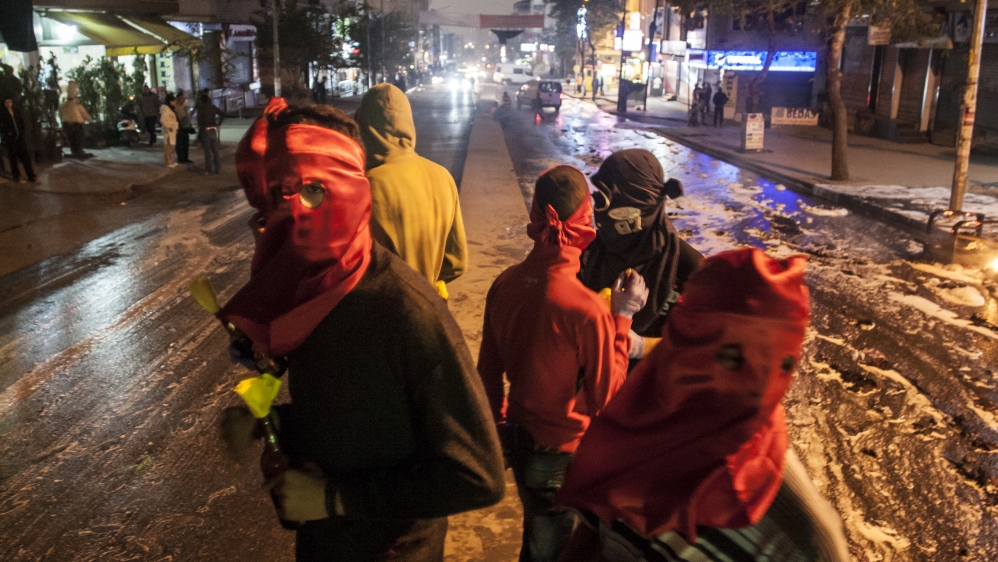 Masked protesters stand on a barricade during minor clashes with Turkish security forces during a protest against Saturday's Ankara bombing attacks, in Istanbul's Gazi district [AP]