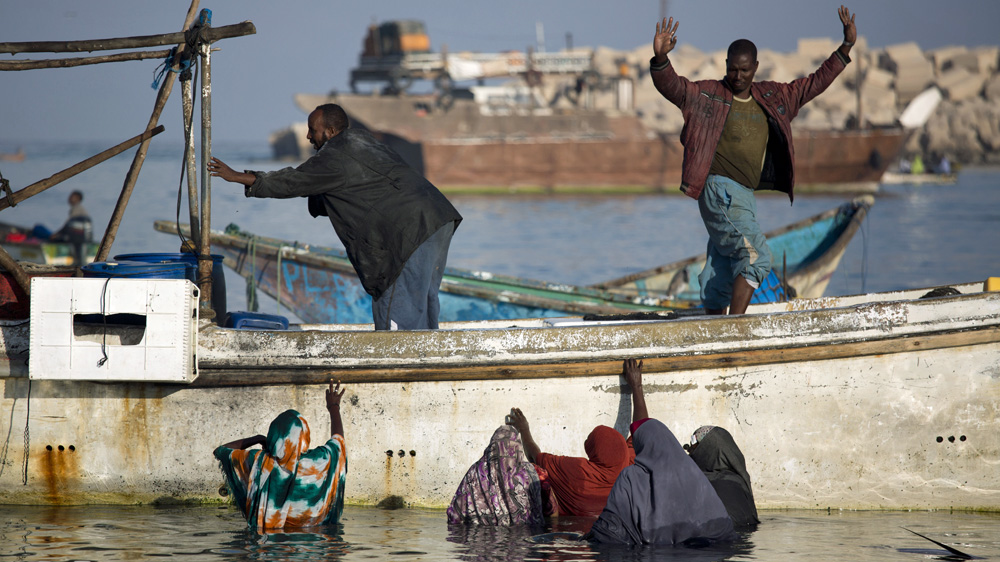 A fisherman tells Somali women there are no more fish at the Bosaso harbour in Puntland [Karel Prinsloo/Adeso]