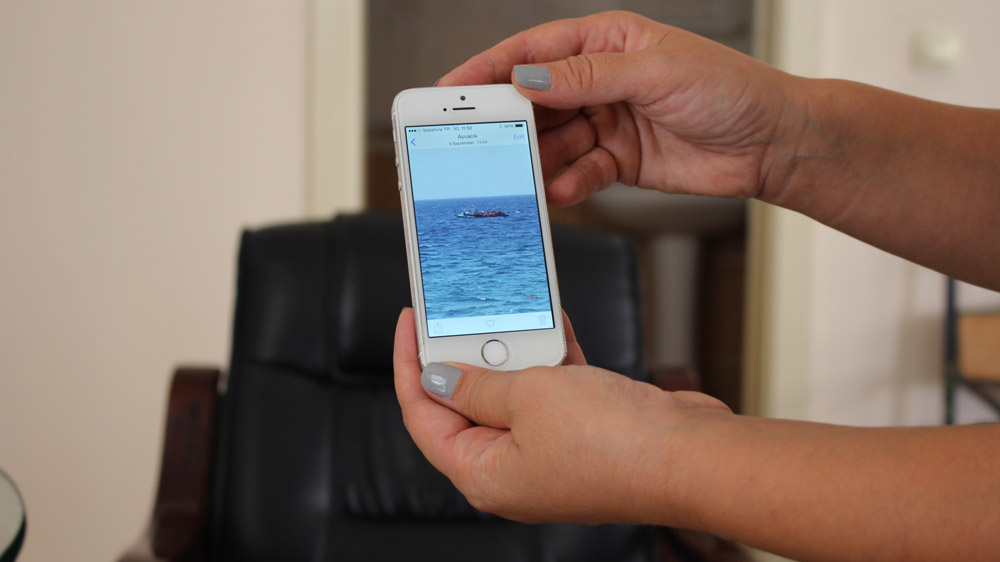 Aylin shows a photo she took from her house of a dinghy of refugees heading to Greece [Kevin Kusmez/Al Jazeera]
