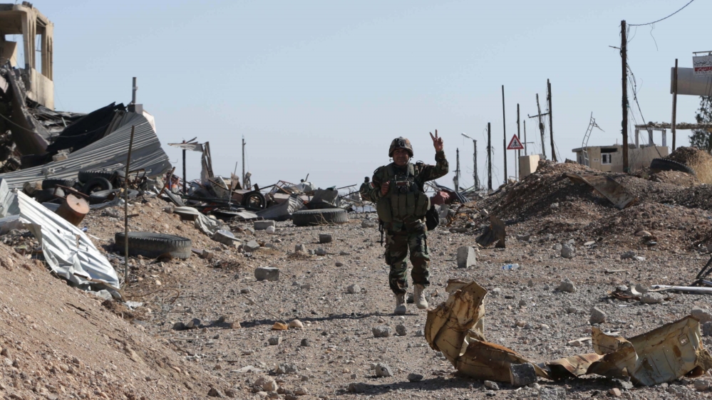 A Kurdish Peshmerga fighter flashes the victory sign as he walks thrpugh the town of Sinjar aft