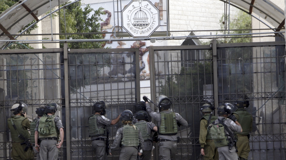 An Israeli border policeman aims breaks into a university