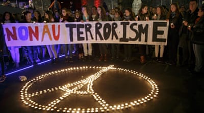 People gather around a peace sign with the Eiffel Tower, realised by candles, during a rally for the victims of the terrorist attacks in Paris, in Lausanne, Switzerland [AP]