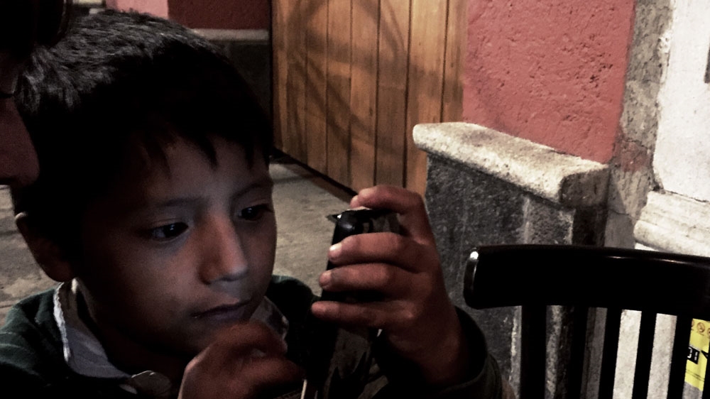 Fernando is wowed by a diner's smartphone. He looks forward to the day he can afford one of his own [Alejandro Saldívar/Al Jazeera] 