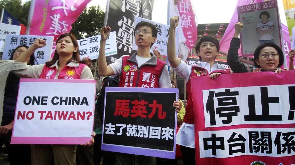 Opposition protesters shout slogans with placards opposing the planned meeting in the Taiwanese capital, Taipei [Chiang Ying-ying/AP] ) 