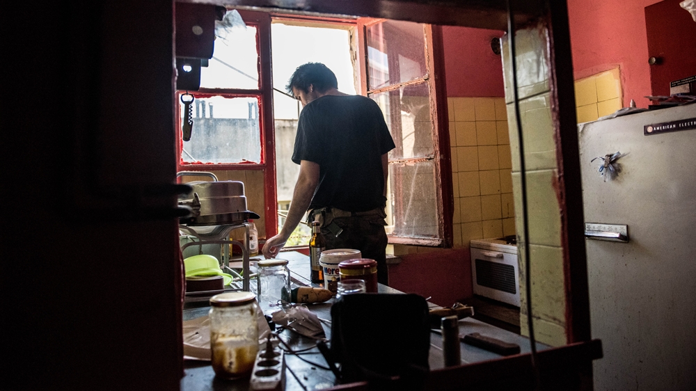 Vagelis stands at the window of the apartment in which he squats in Athens [Tommy Trenchard/Al Jazeera]