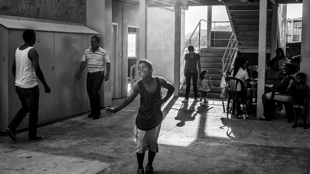 A child dances during a family meeting on the ground floor of a building in Ciudad Zamora [Alejandro Cegarra/Al Jazeera] 