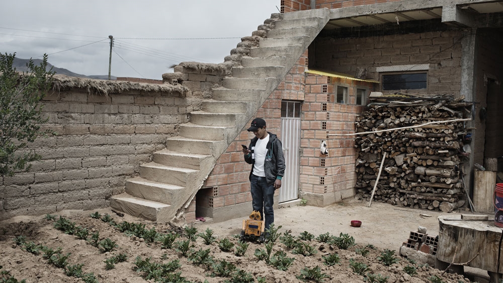 
Quispe stands in his family's courtyard with his robot Wall-E which he can control directly from his mobile phone [Valentino Bellini/Al Jazeera]

