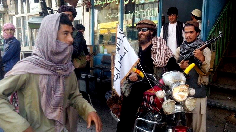 A Taliban fighter sits on his motorcycle adorned with a Taliban flag on a street in Kunduz, Afghanistan [AP]
