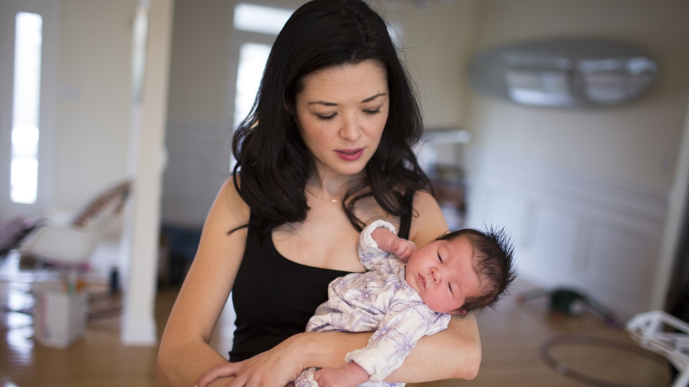 Ashlyn Nelson holds her four-week-old daughter, Suvi. Nelson is an economist and associate professor at Indiana University-Bloomington [James Brosher/Al Jazeera]  
