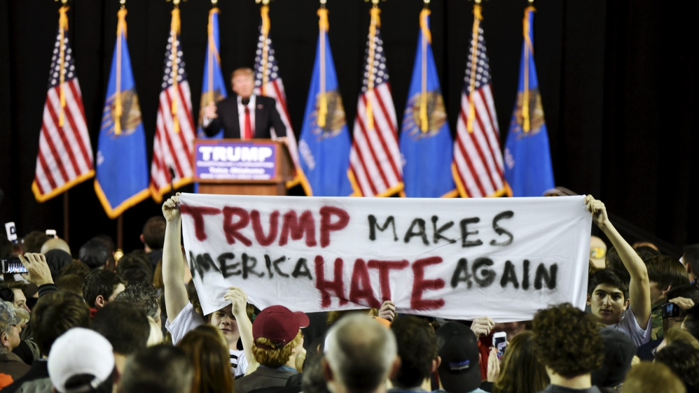 Protestors hold up a sign towards the crowd at a rally for U.S. Republican presidential candidate Donald Trump at Oral Roberts University in Tulsa, Oklahoma
