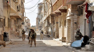 Forces loyal to Syria's President Bashar al-Assad walk with their weapons in Palmyra city after they recaptured it [Reuters]