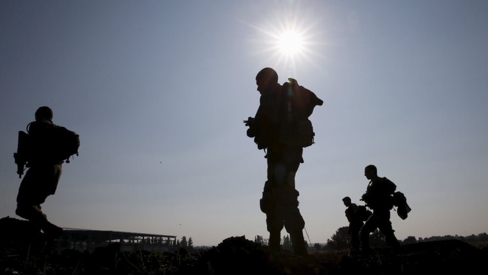 Israeli soldiers are silhouetted as they search for remains of rockets fired from Lebanon on Sunday, near Nahariya