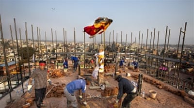 Buddhist pilgrims work on the reconstruction on the top side of the Boudha stupa, which is listed as a UNESCO World Heritage Site, in Kathmandu, Nepal [EPA] 