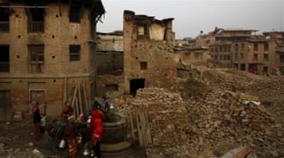 People fetch water from a well near the debris of collapsed houses damaged during the April 2015 earthquake, in Bhaktapur, Nepal [Reuters]