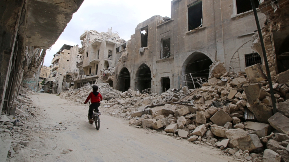 A boy rides a bicycle near damaged buildings in the rebel held area of Old Aleppo