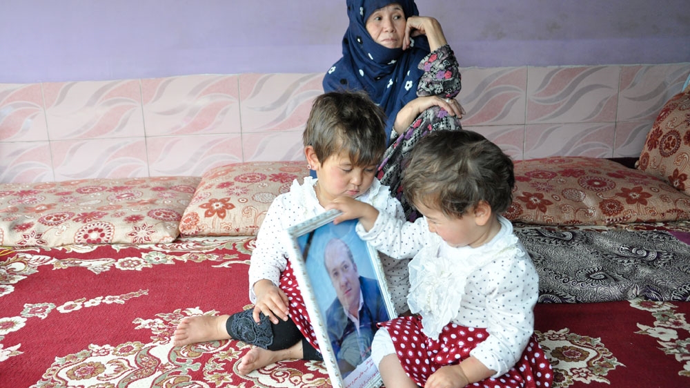 Sitaeesh, left, smiles at her late father's picture  [Fatima Faizi/ Al Jazeera]
