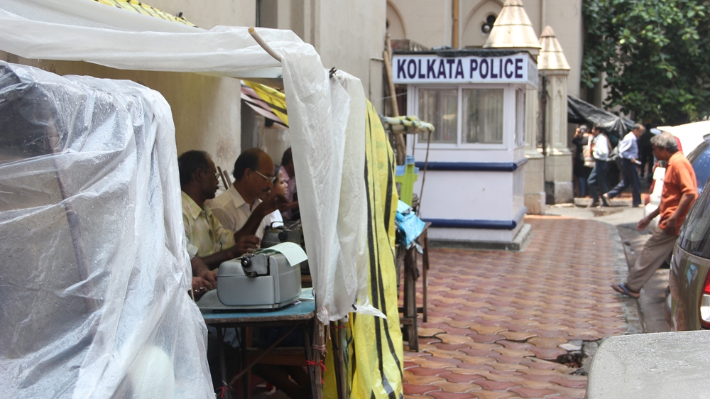 Plastic sheets protect typists from the elements [Swati Sanyal Tarafdar/Al Jazeera] 