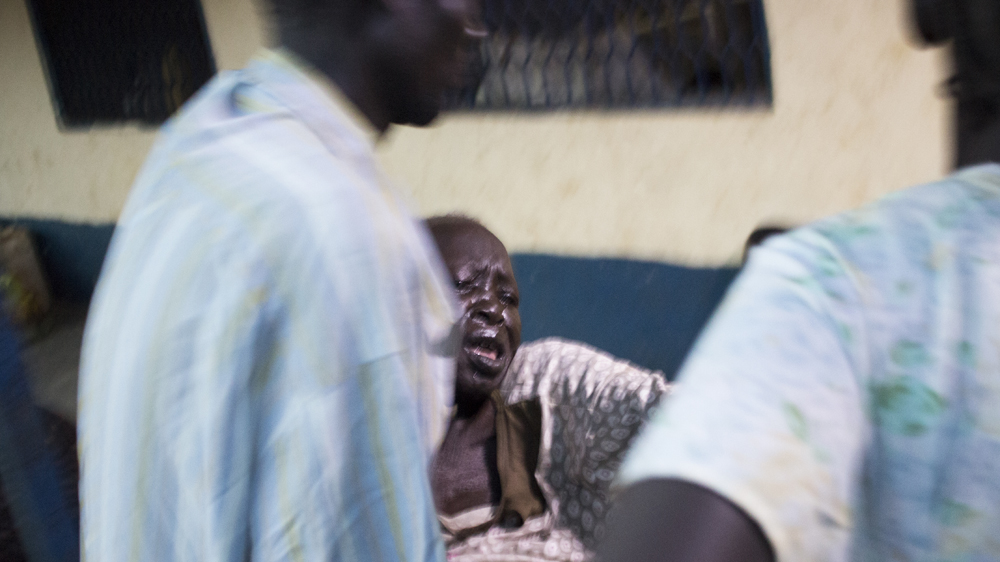 When Abang arrives at the hospital she is carried in by a man from the village and her daughter [Henry Wilkins/Al Jazeera]