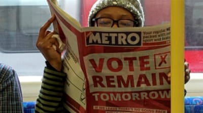 A woman reads a newspaper on the Underground in London [Reuters]